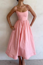 Pink midi dress with thin straps, fitted bodice, and gathered skirt at waist