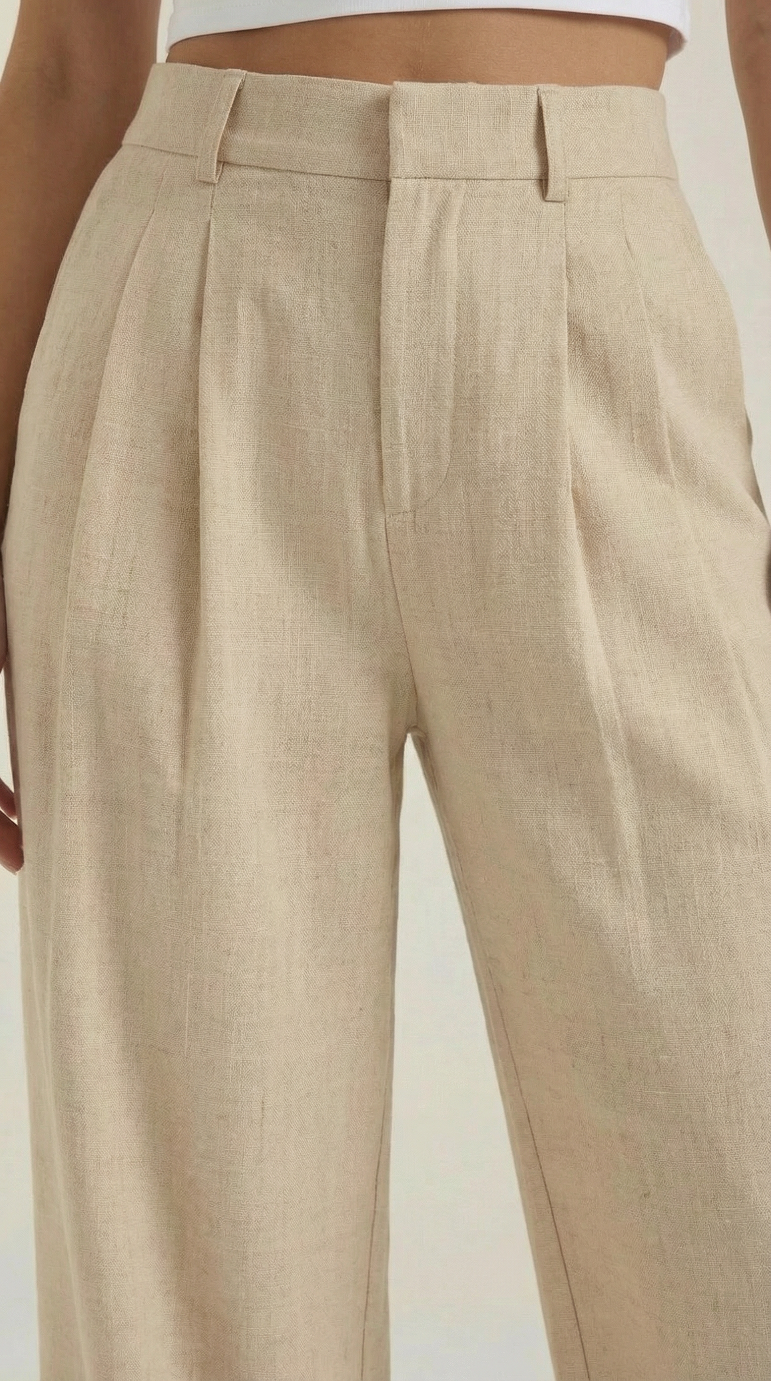Beige pleated high-rise wide-leg pants, front close-up with belt loops.