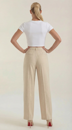 Beige high-rise pleated wide-leg pants on model, back view with waistband.