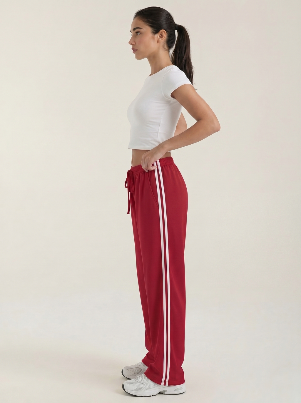 Women's red wide-leg track pants with drawstring elastic waist and white side stripe.