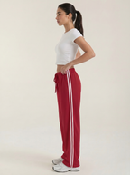 Women's red wide-leg track pants with drawstring elastic waist and white side stripe.
