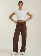 Women's brown wide-leg track pants with drawstring elastic waist and side stripes.